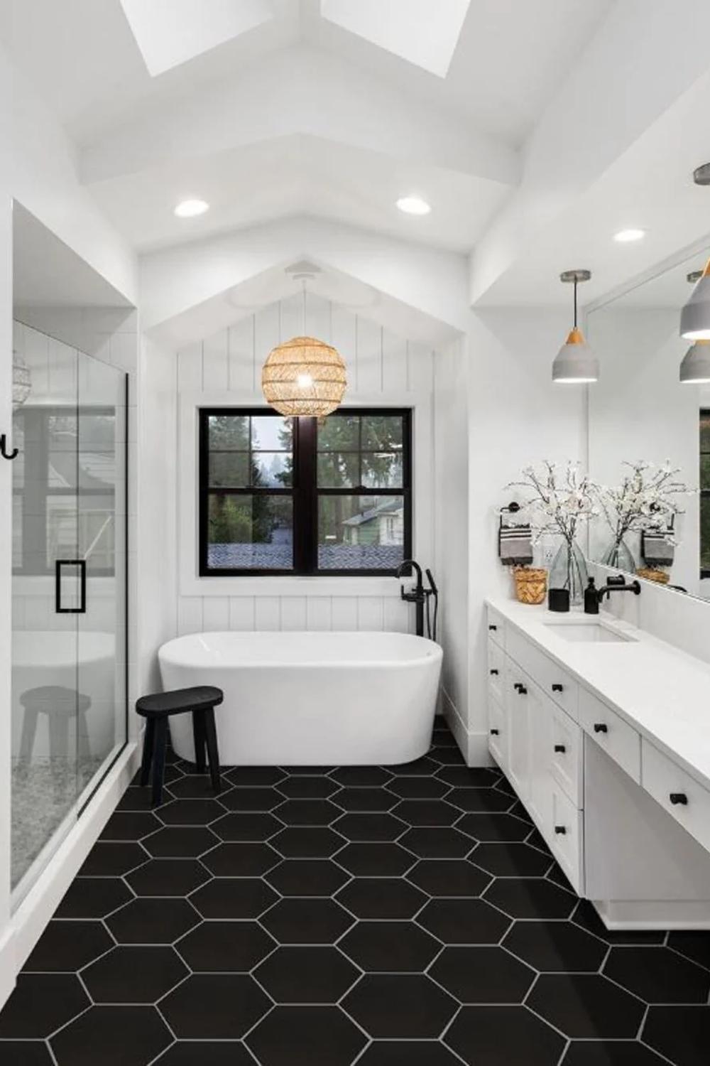 Baño blanco y negro con azulejos hexagonales en el suelo y bañera moderna