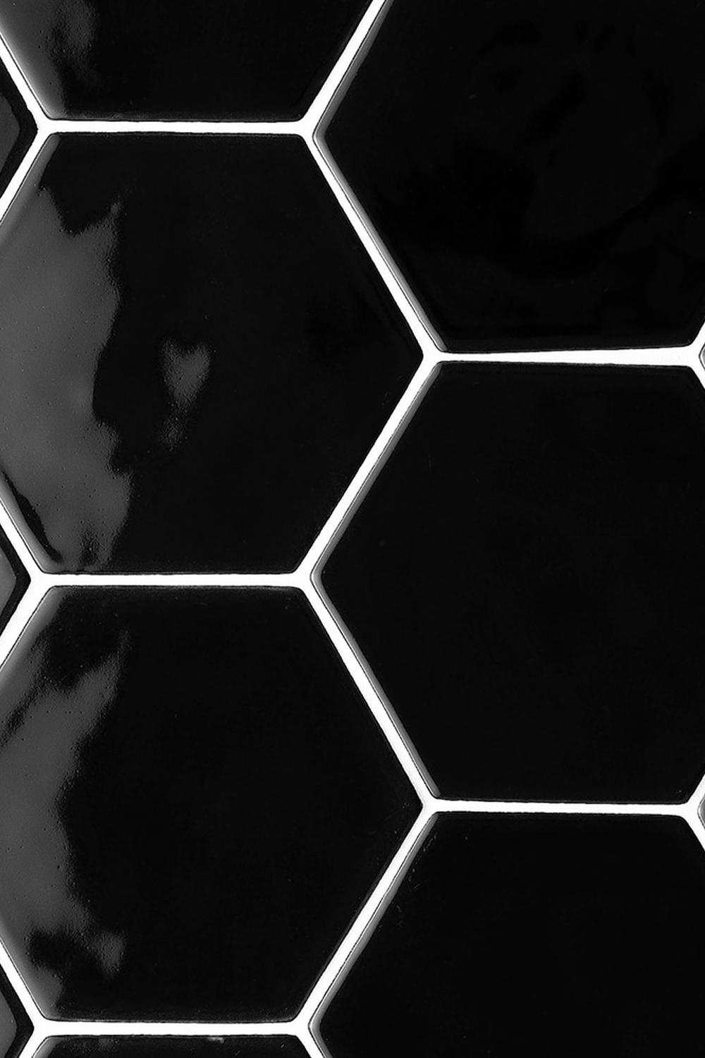 Bathroom with black hexagon tiles illuminated by stylish light fixtures.