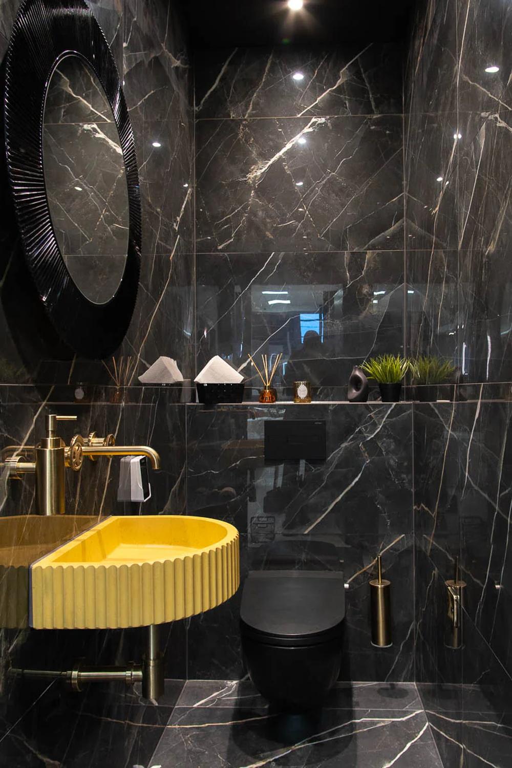 Baño moderno con azulejos de mármol negro y detalles dorados