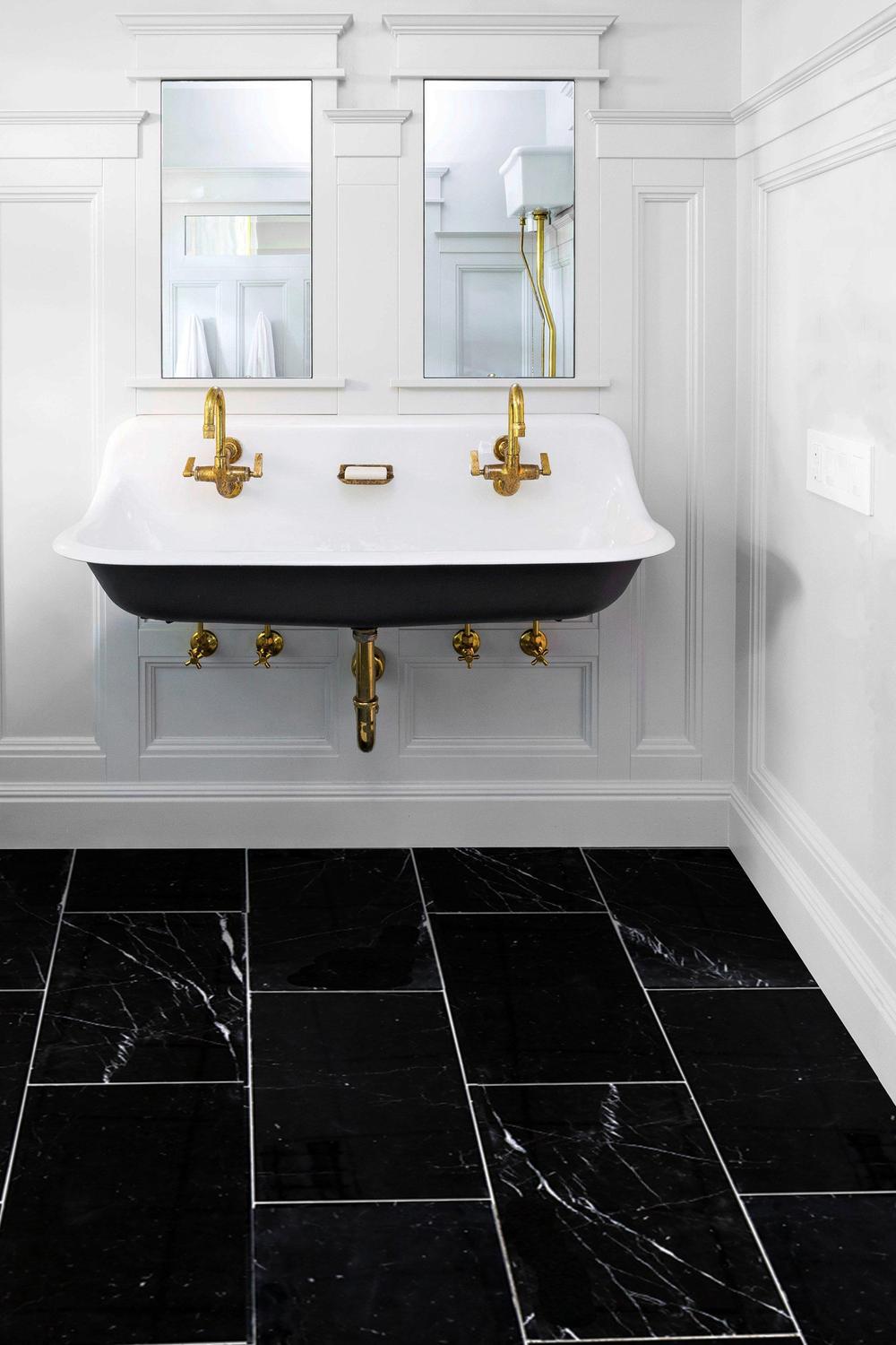 Baño clásico con azulejos de mármol negro y toques dorados