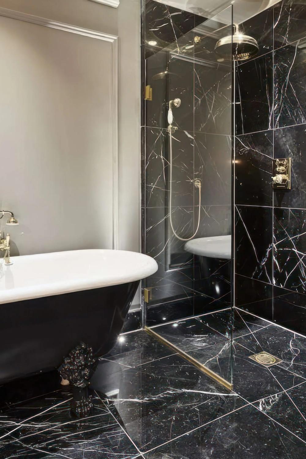 Baño elegante con mármol negro y bañera de pie