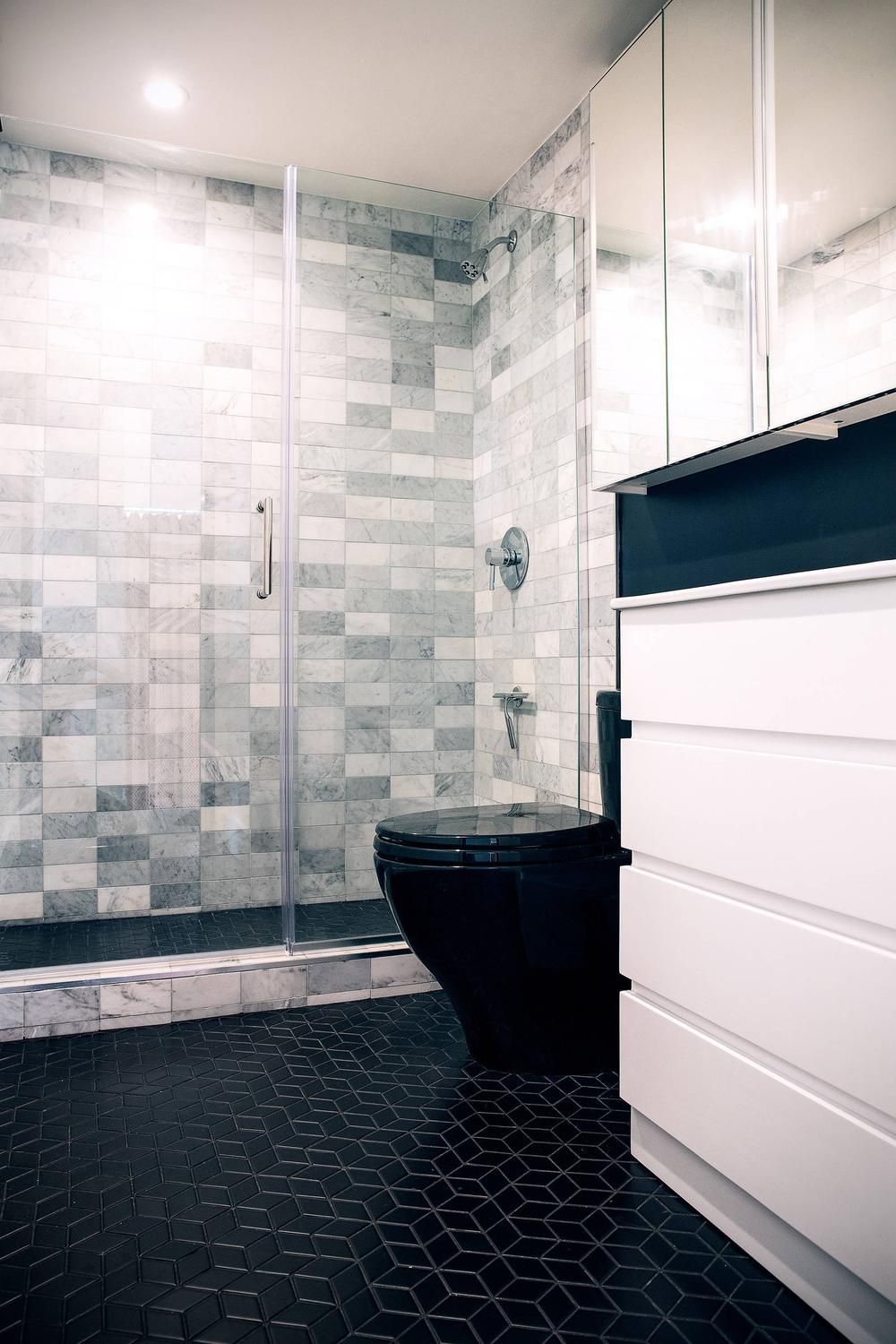Baño moderno con azulejos geometrizantes y mármol negro