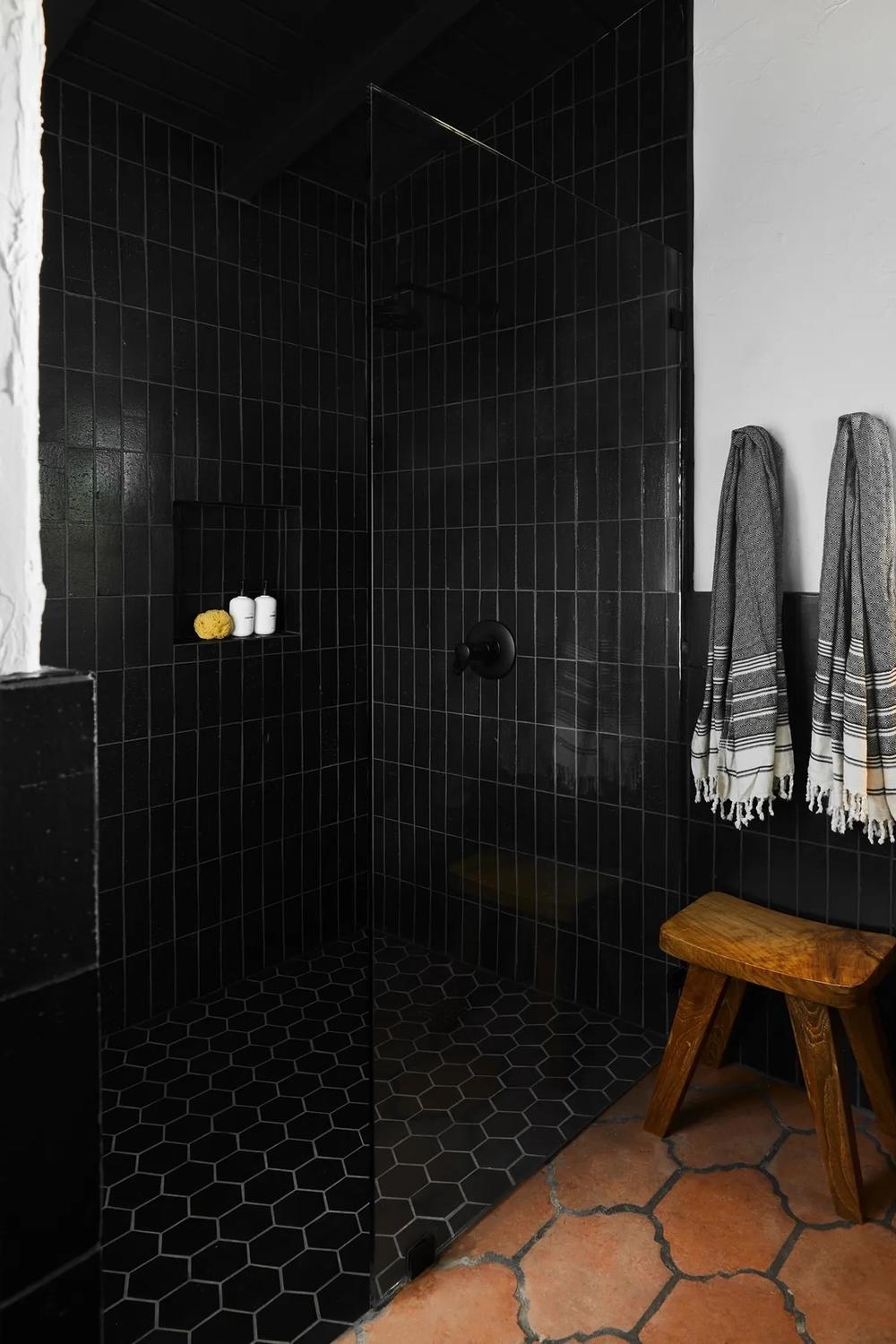 Baño elegante con ducha negra y mampara de cristal