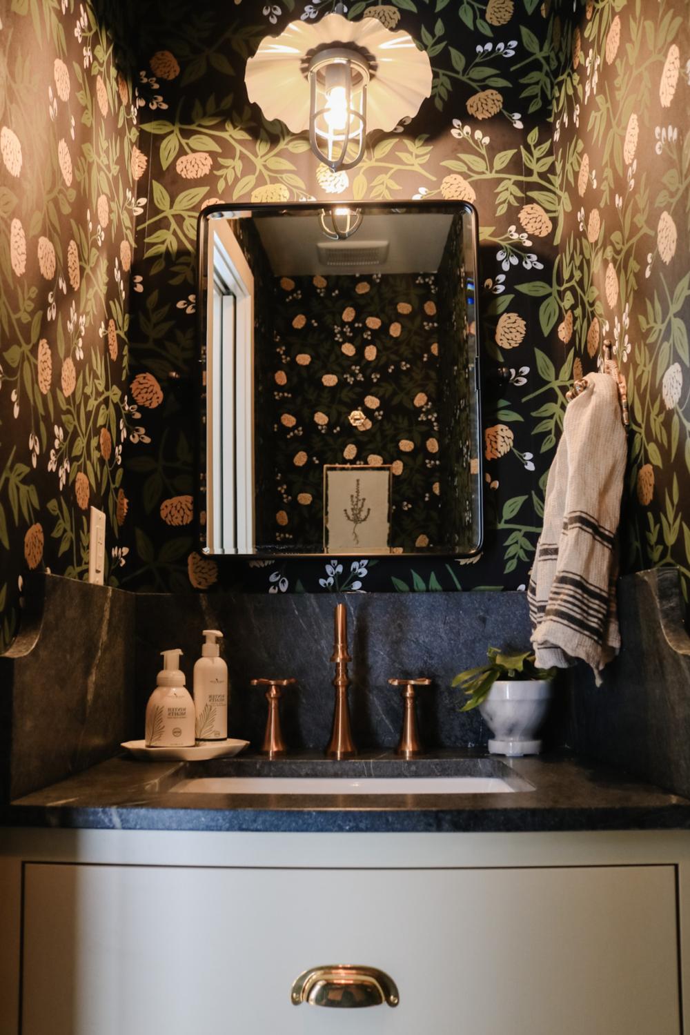 Compact bathroom with bold black wallpaper featuring floral and pine cone designs.