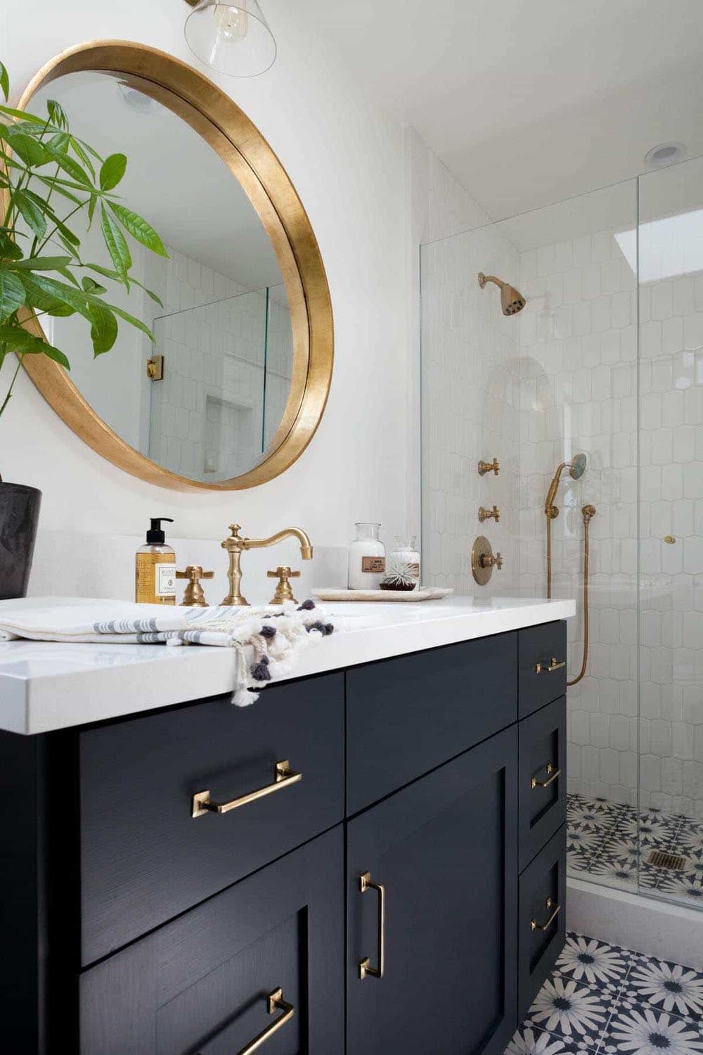 A sleek contemporary bathroom with flawless black cabinetry and gold hardware.