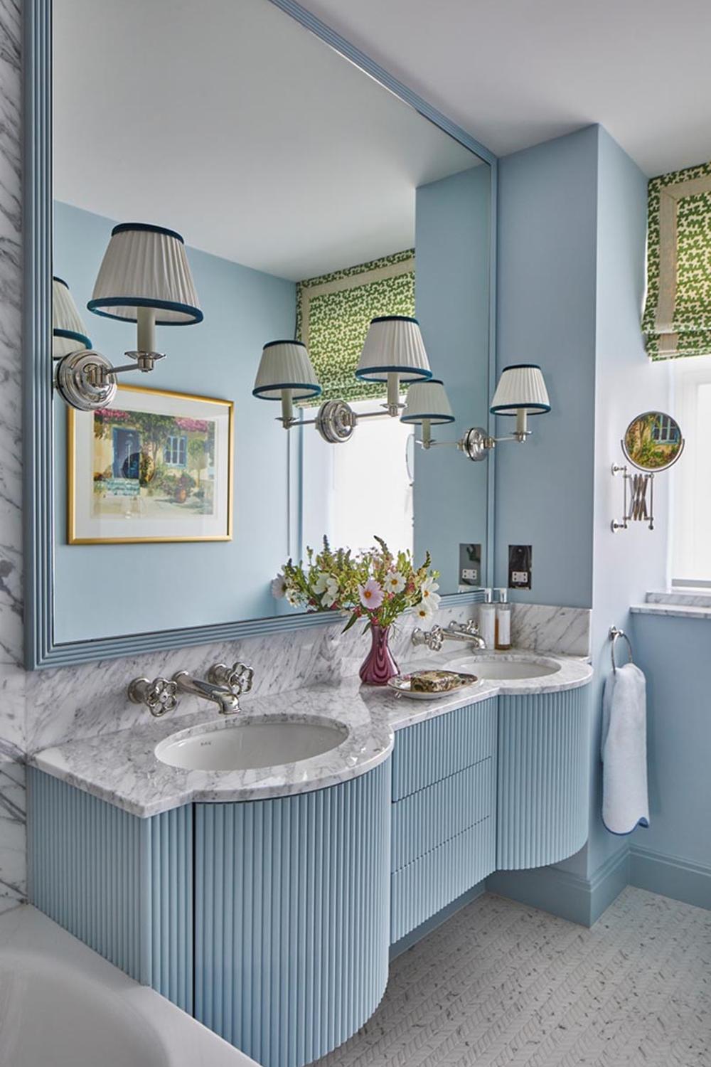 A stylish blue bathroom with a uniquely designed curved vanity