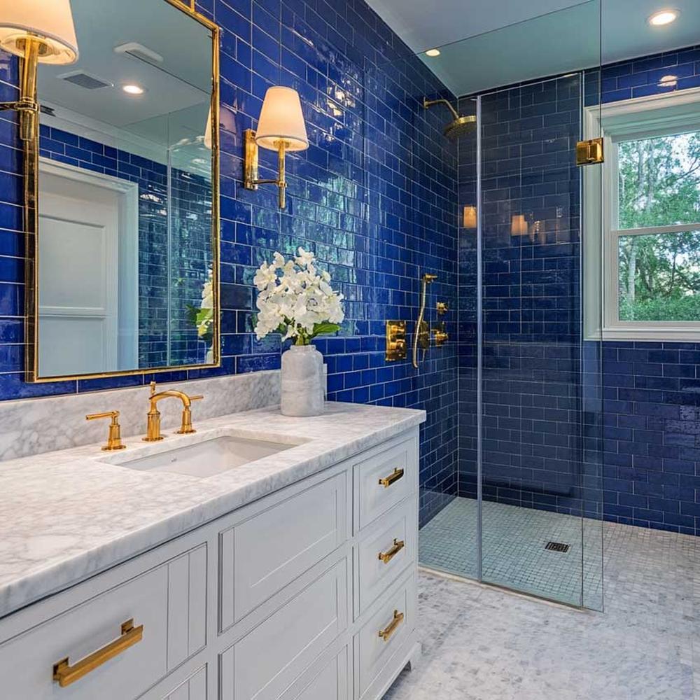 An elegant bathroom with deep blue glossy wall tiles and gold accents