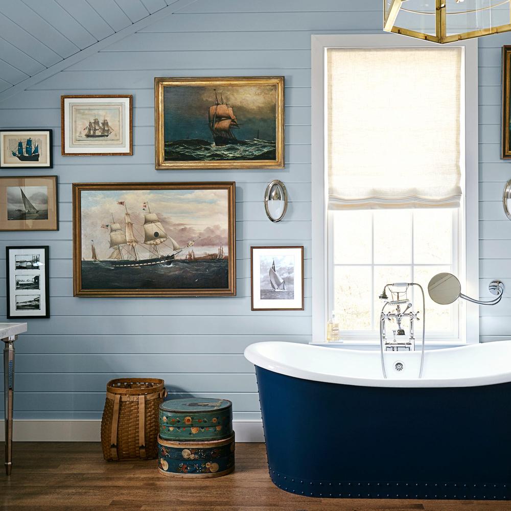 A serene blue bathroom with nautical-themed artwork and decor