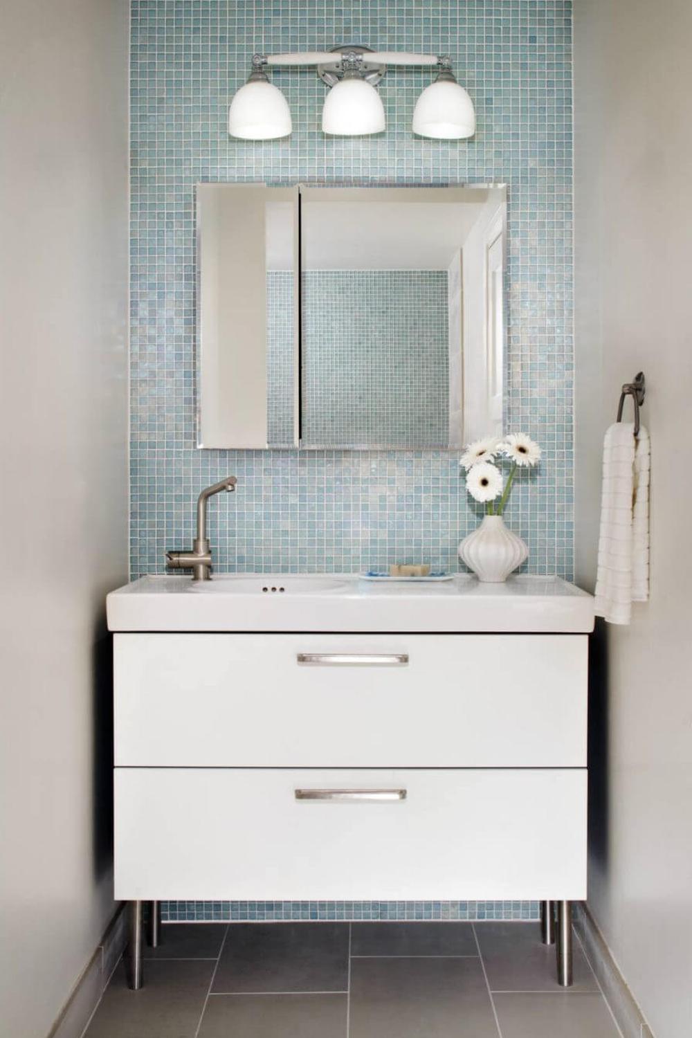 Modern bathroom featuring personalized touches with blue mosaic tiles and sleek fixtures.