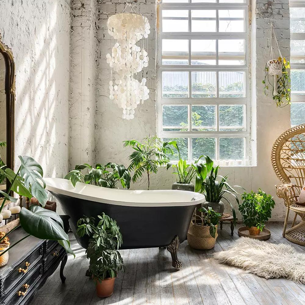 A vintage clawfoot bathtub in a bohemian bathroom setting, surrounded by plants and soft lighting.