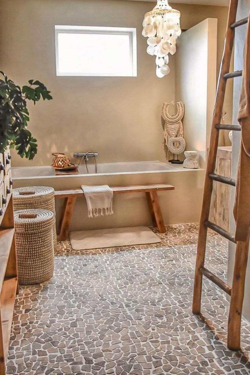 A minimalist bohemian bathroom with a freestanding bathtub beside a window.