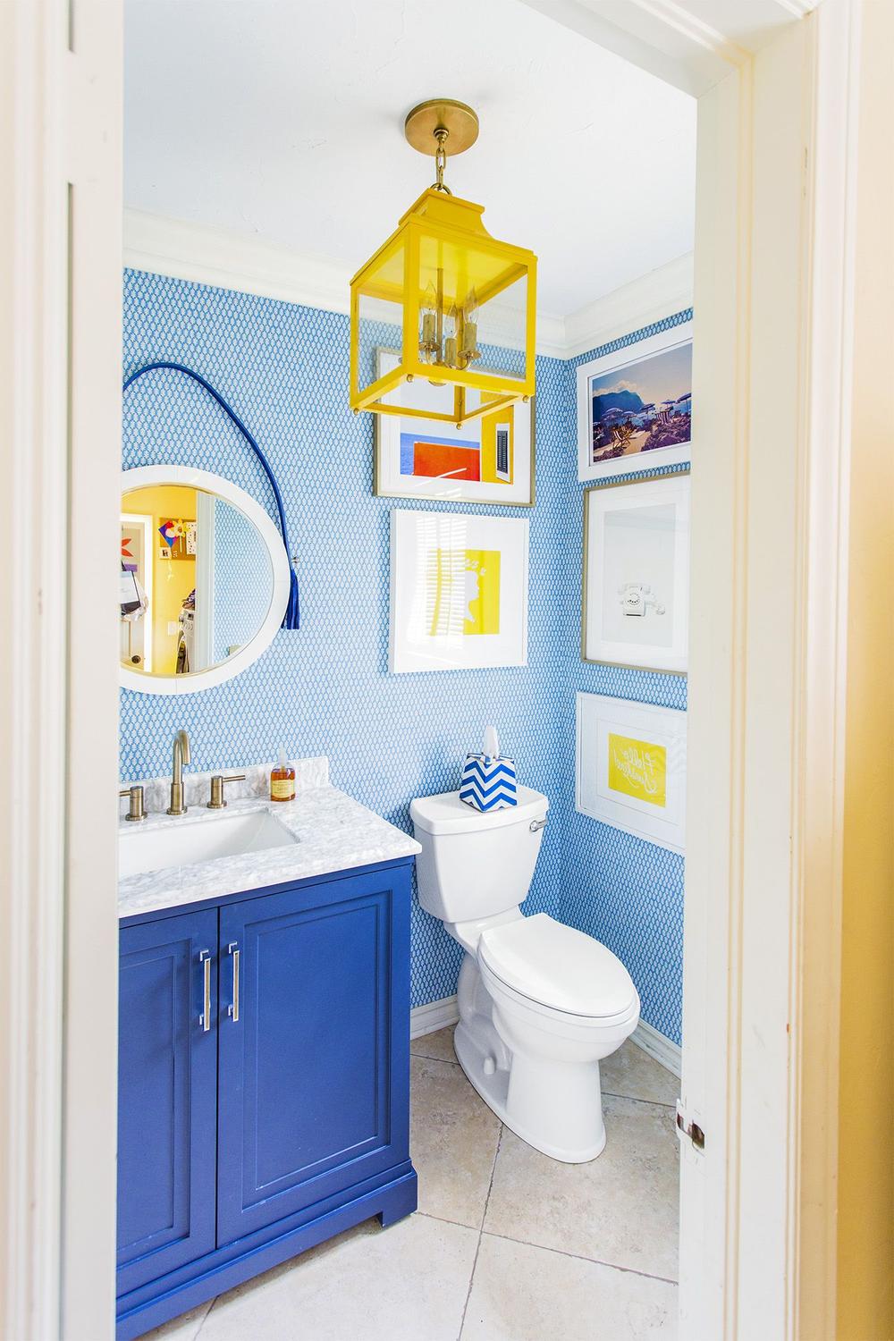 Compact bathroom with vibrant blue patterned wallpaper and cheerful decor.