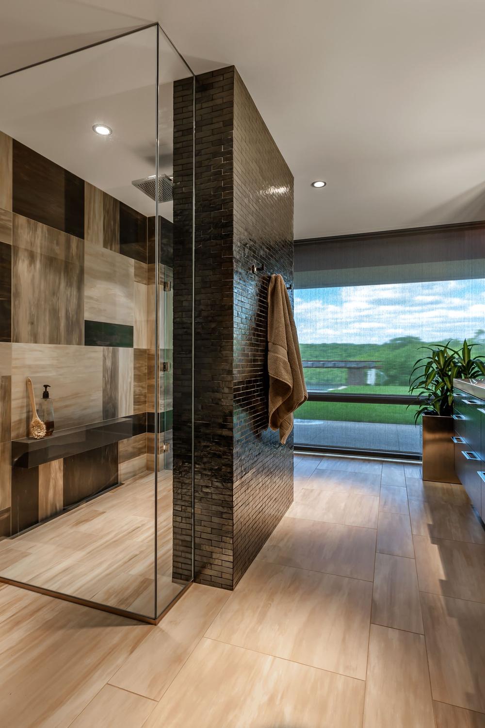 Cuarto de baño contemporáneo en tonos marrones con ducha de cristal y azulejos texturizados.