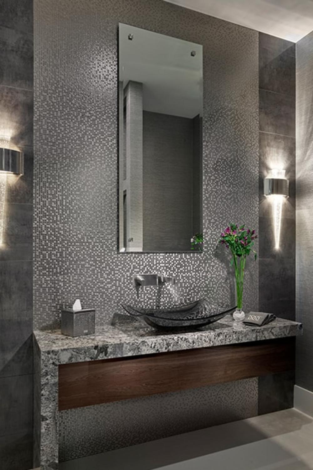 Baño contemporáneo con texturas elegantes y lavabo negro sobre encimera de granito.