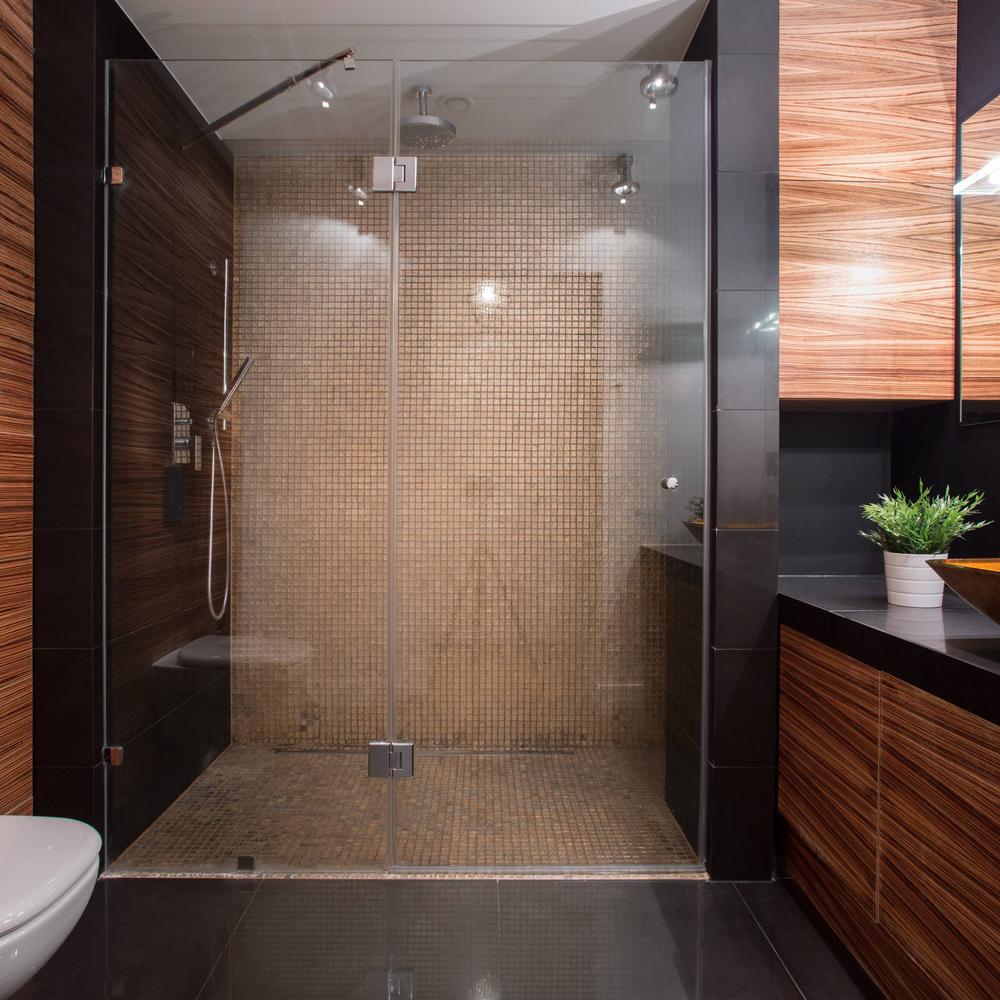 Baño moderno con ducha de cristal y azulejos en tonos marrones claros.