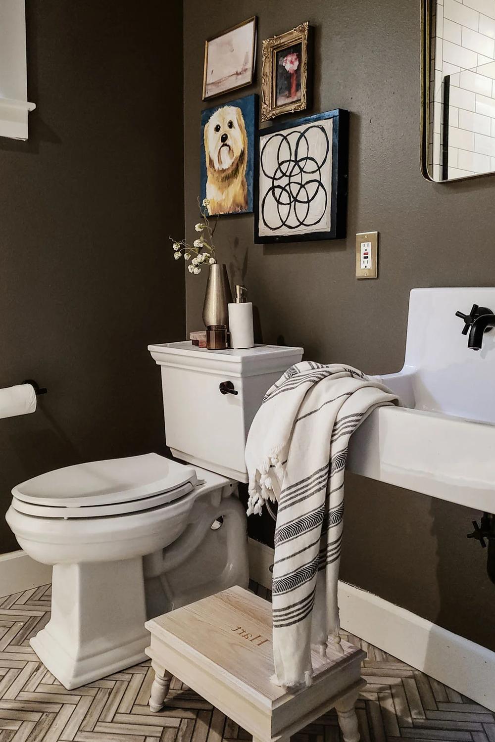 Baño decorado en verde profundo con obras de arte