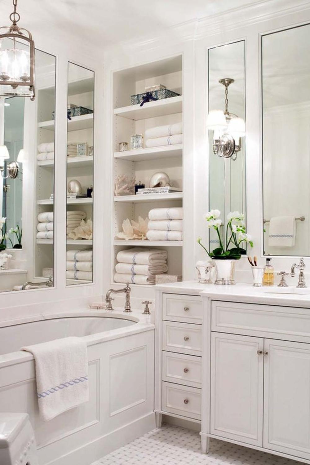 Bathroom shelves between mirrors showcasing third-dimensional storage with decorative boxes and neatly stacked towels.