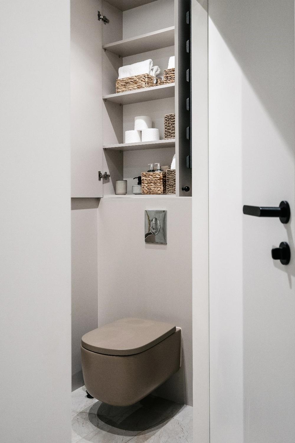 Compact bathroom with practical storage shelves above the toilet, elegantly organized for easy access.
