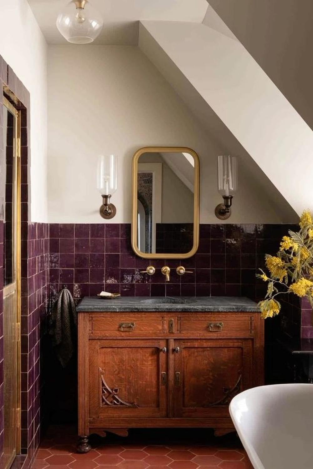 A vintage-inspired bathroom showcasing burgundy tiles and intricate wooden details.