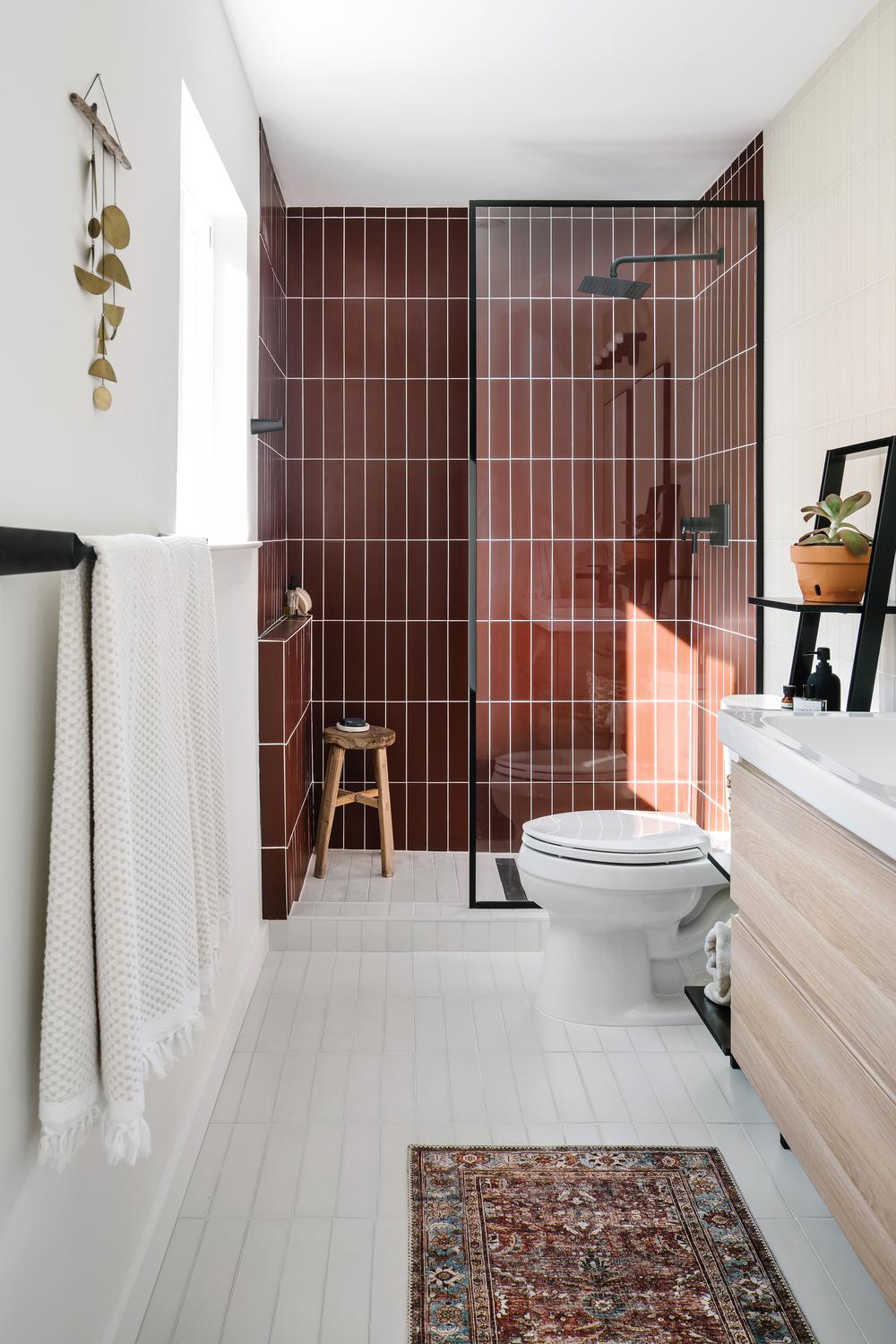 A stylish bathroom featuring burgundy tiles and decorative elements.