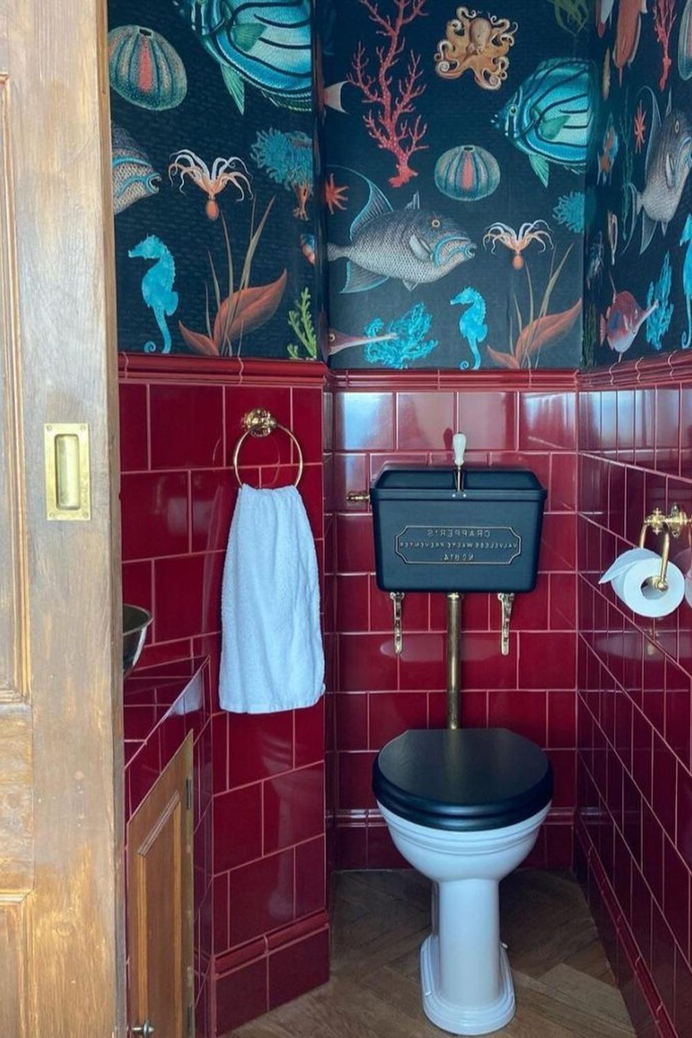 A compact bathroom featuring bold burgundy tiles and vibrant accents.