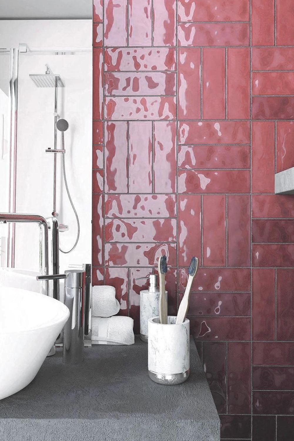 A modern bathroom featuring striking burgundy tiles and glass elements.
