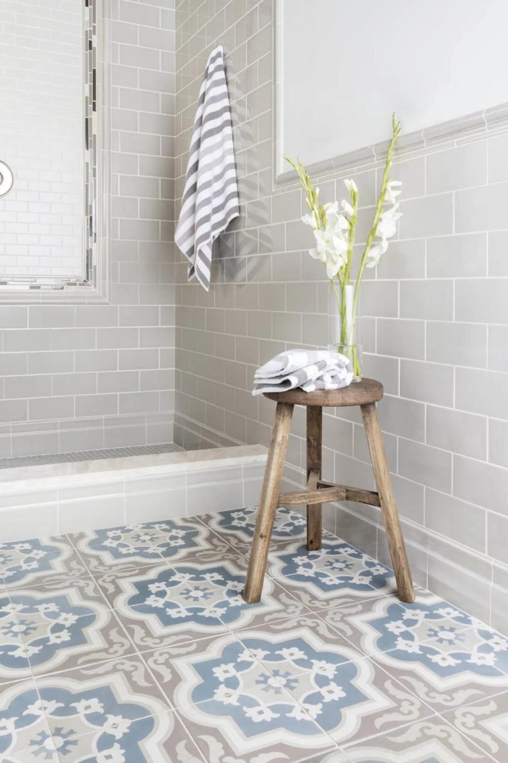 Charming bathroom with blue, cream, and gray geometric cement tile flooring paired with light subway tiles.