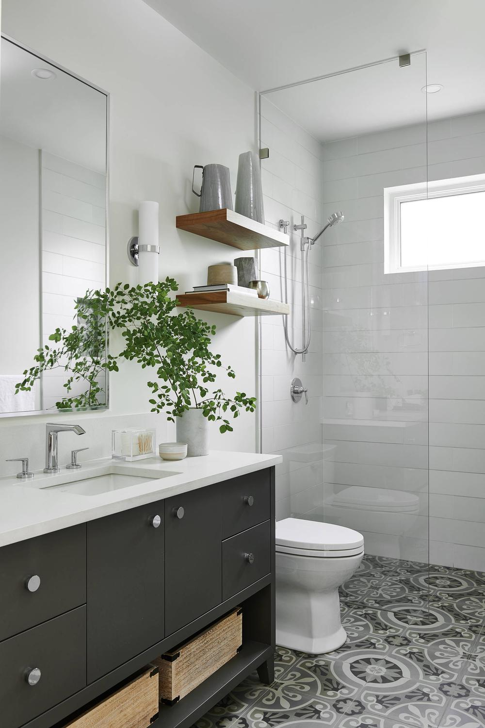 Modern bathroom showcasing a sleek gray vanity with chrome accents and geometric cement tile flooring.