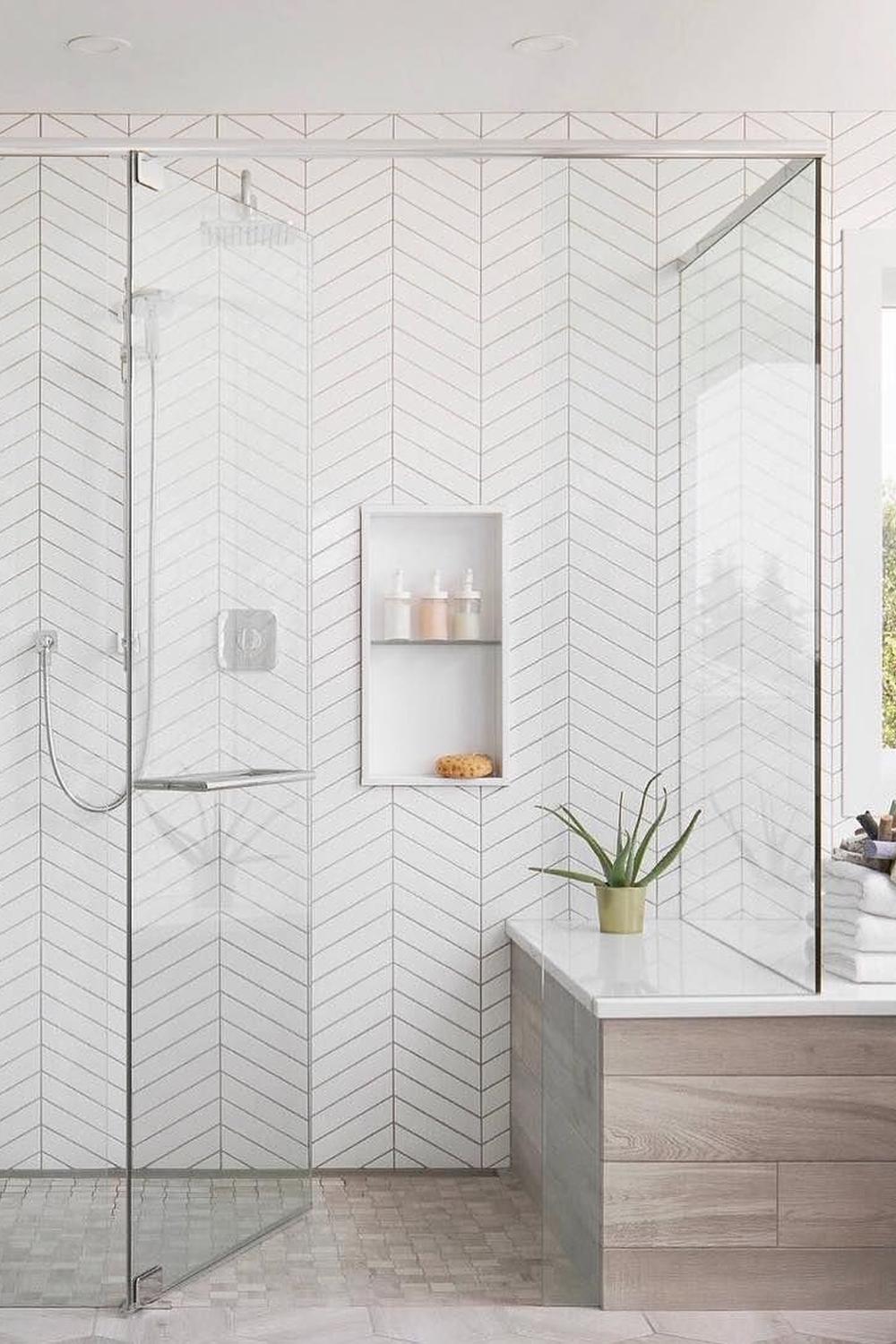 Baño moderno con azulejos en chevron blancos y detalles minimalistas.