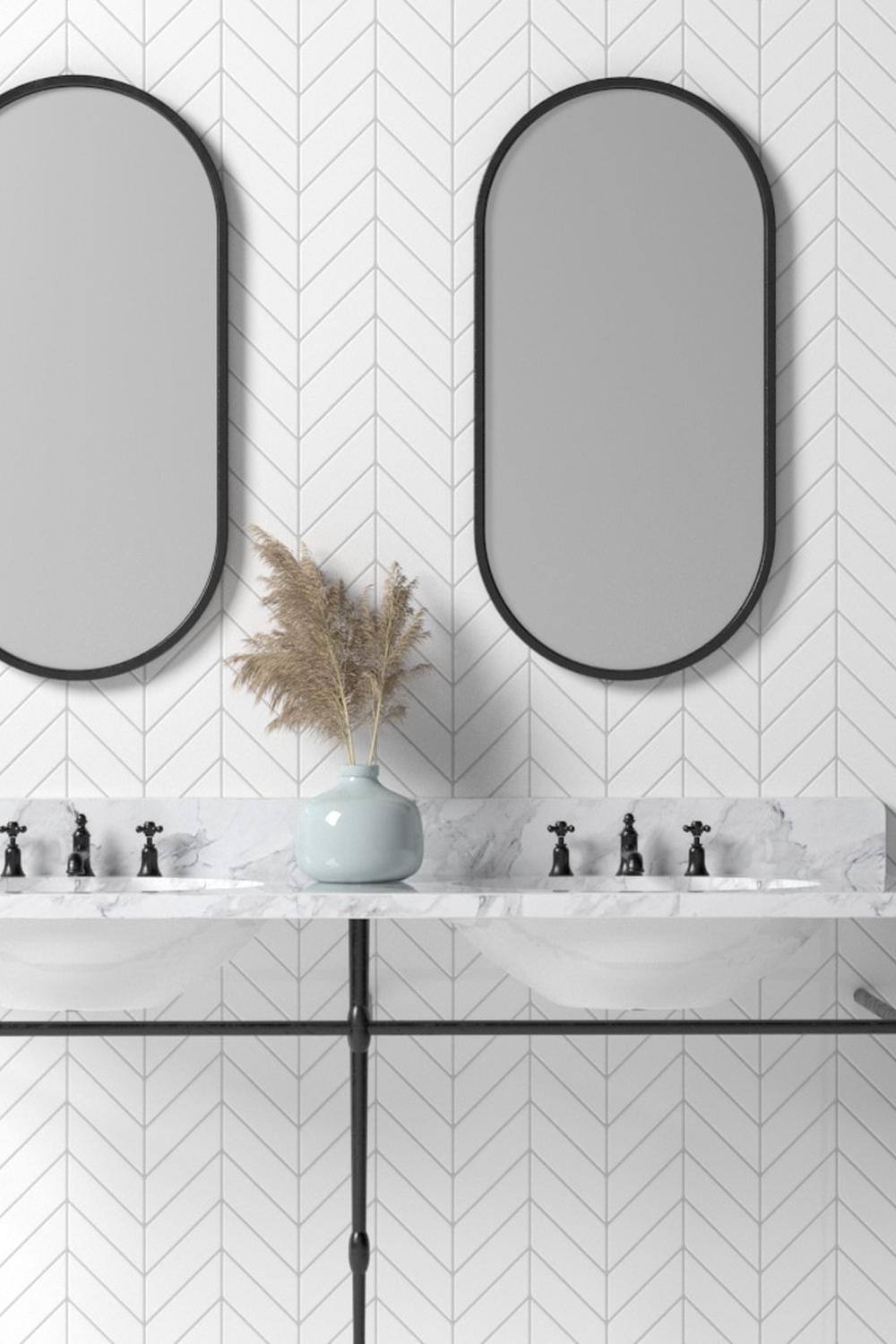 Baño moderno con azulejos en chevron y espejos elegantes.