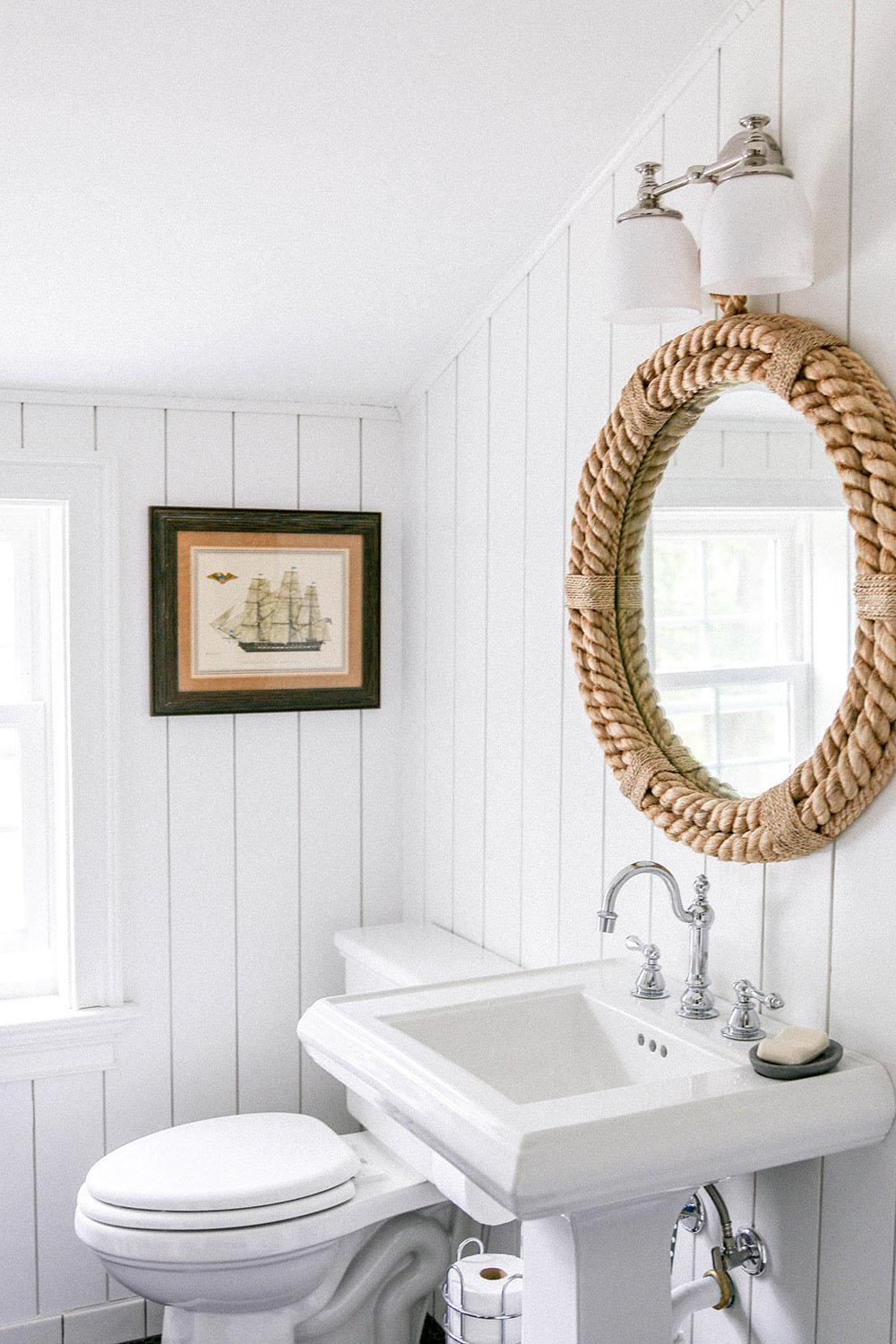 Bright colonial bathroom featuring white shiplap paneling and vintage mirror.