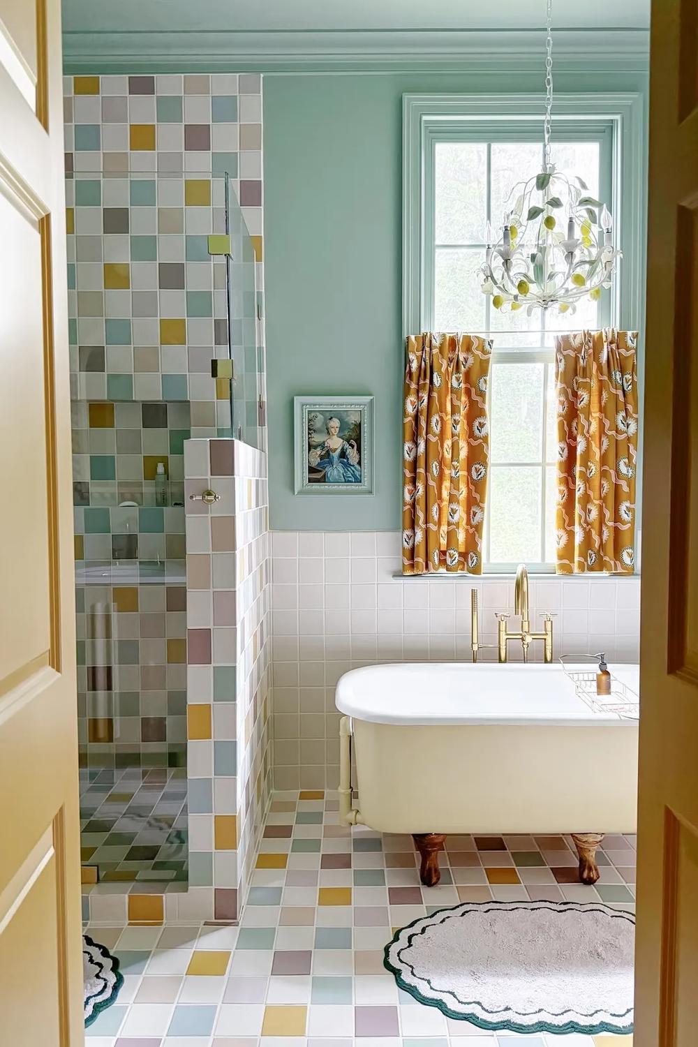 Vintage freestanding bathtub surrounded by a beautiful pastel mosaic tile design.
