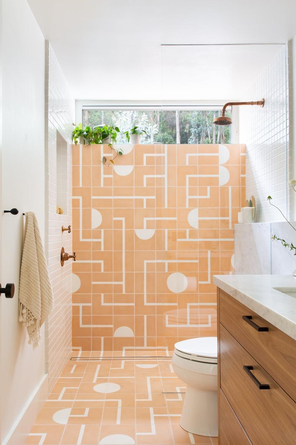 Vibrant bathroom featuring peach tiled walls with geometric patterns and a wooden vanity.