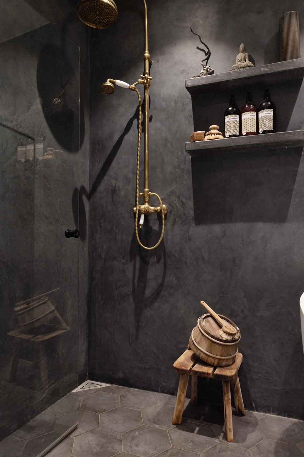 Baño minimalista de hormigón con detalles en dorado