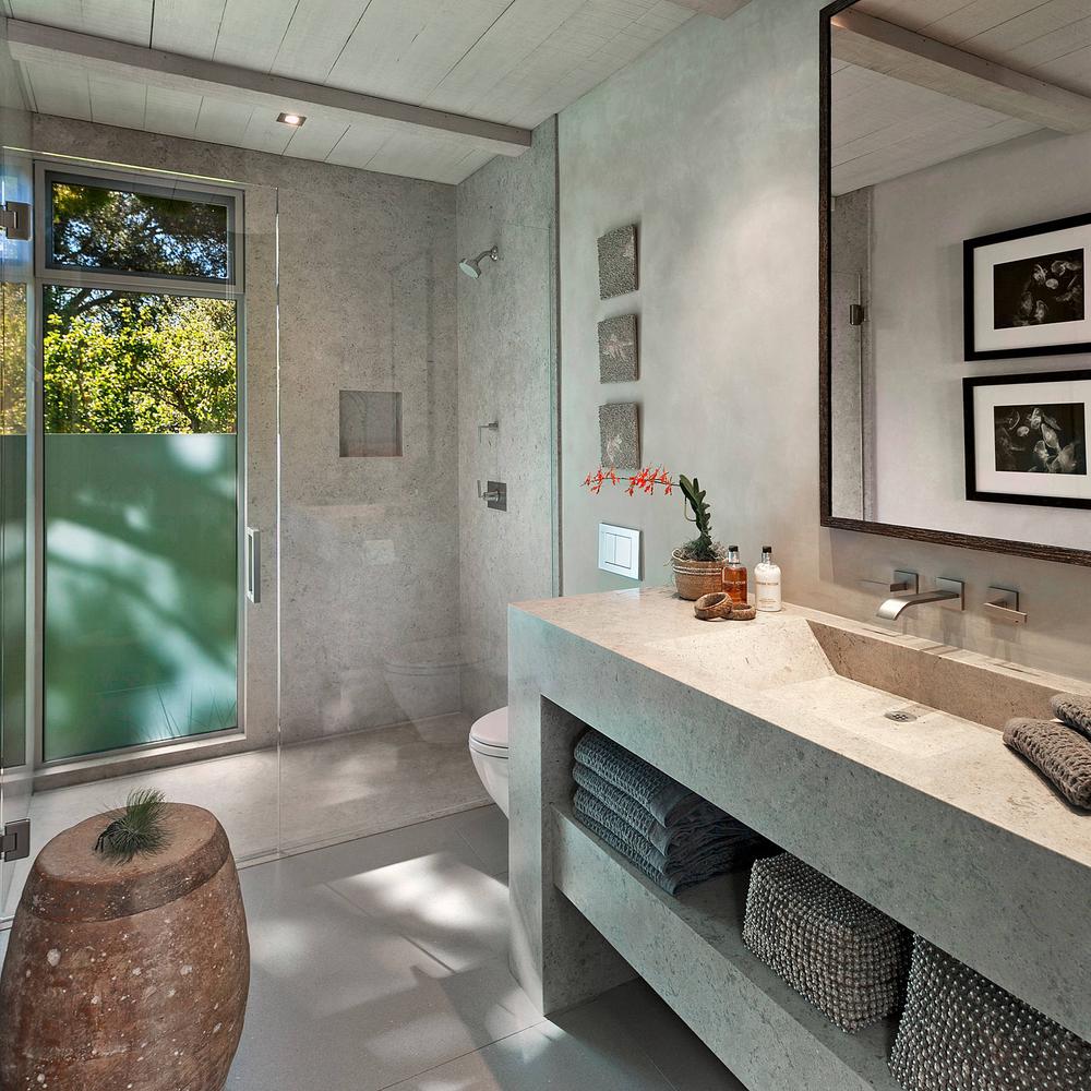 Light Textured Concrete Vanity with Open Shelving featuring a spacious countertop, integrated sink, and neatly organized towels.