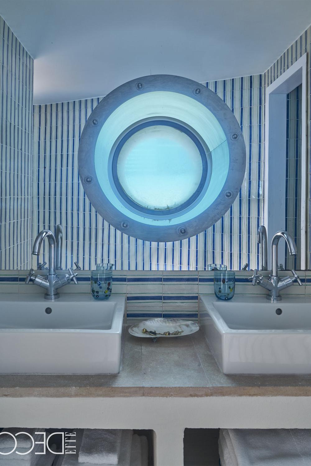Contemporary bathroom with striped walls and a circular porthole window.