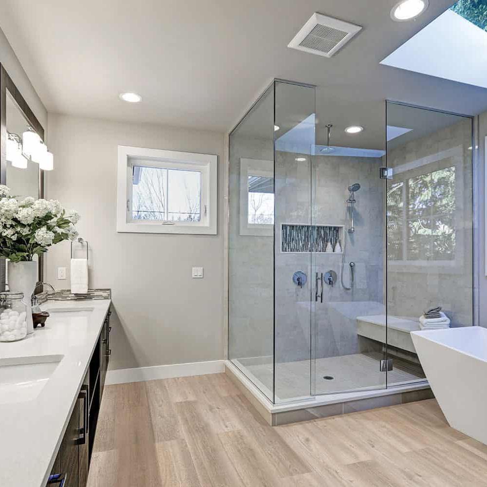 Stylish bathroom with cork flooring, glass shower, and freestanding bathtub