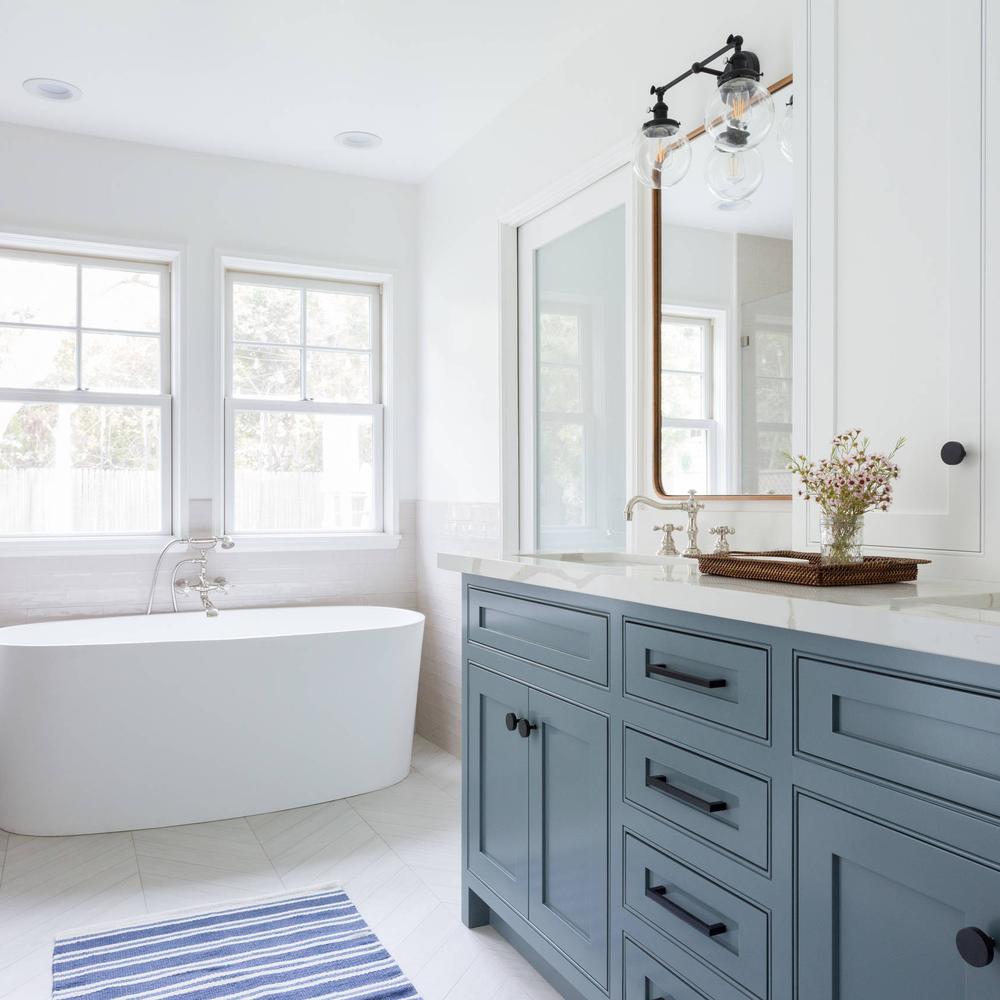 Baño de estilo cottage con armarios azules y baldosas en espiga