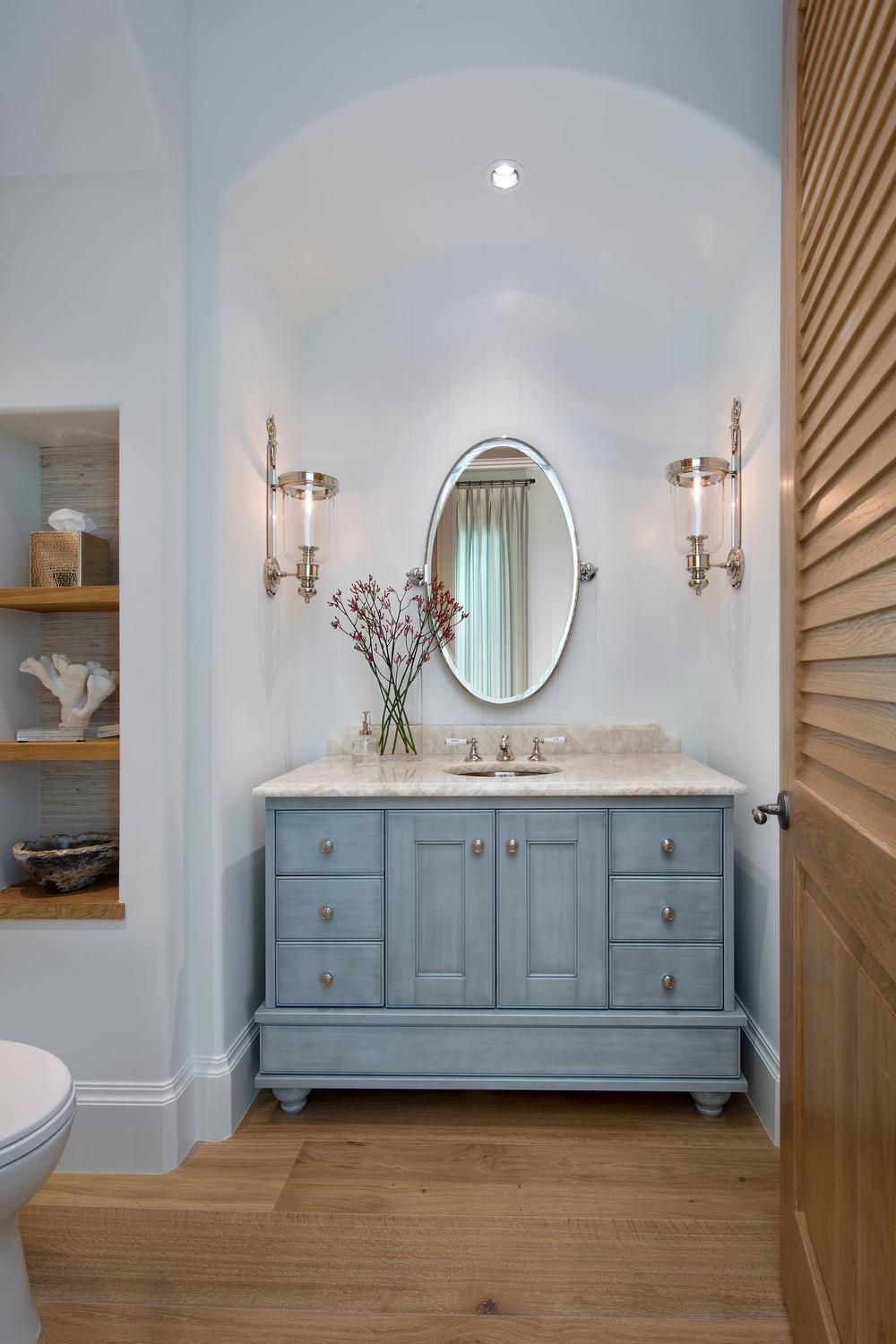 Baño rústico con armarios azules y espejo ovalado