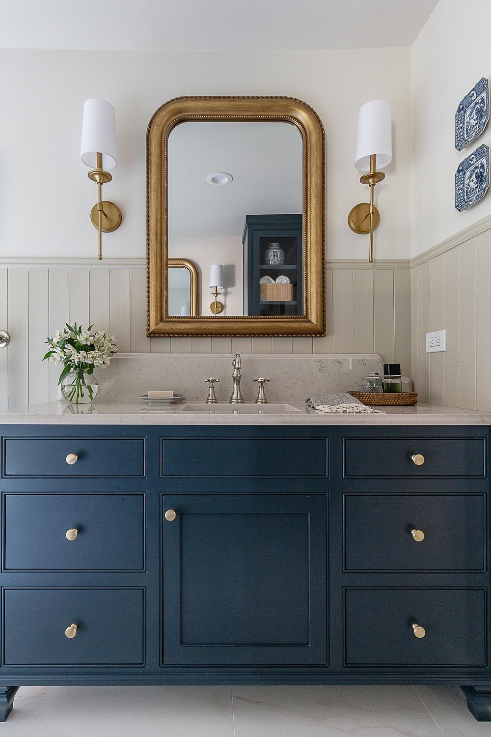Cozy cottage bathroom featuring deep navy cabinetry with elegant finishes and soft accents.