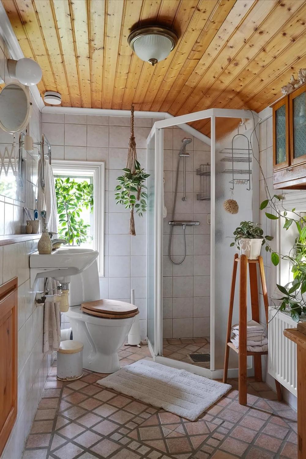 Baño acogedor con techo de madera y luz natural.