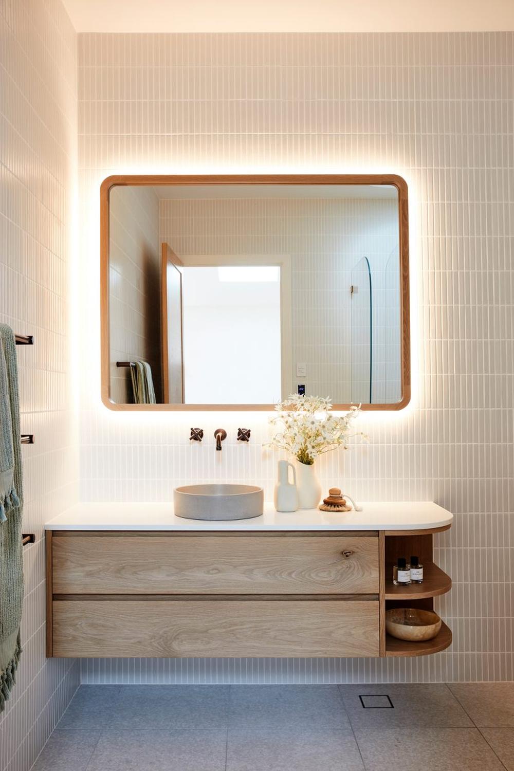 Contemporary bathroom featuring light wood vanity and round gray stone sink.