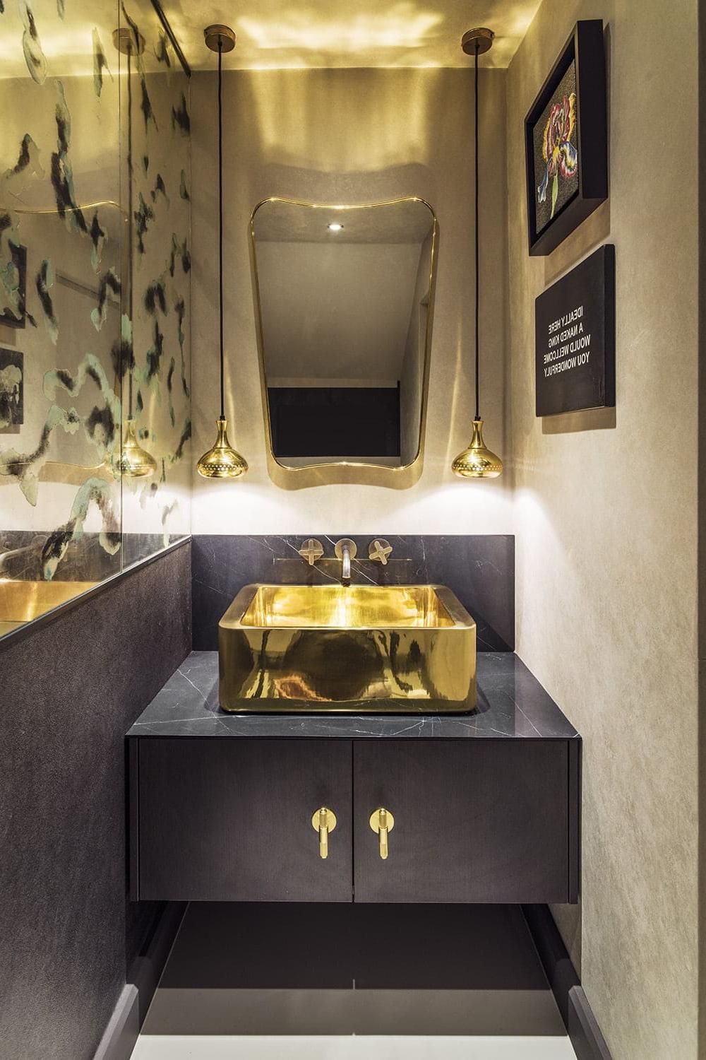 Baño oscuro con toques dorados y diseño moderno