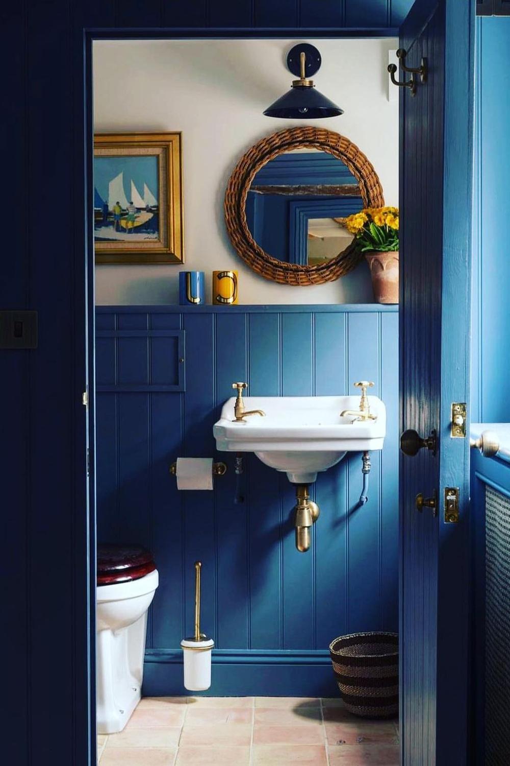 Baño con paneles de madera y azul profundo creando un ambiente acogedor