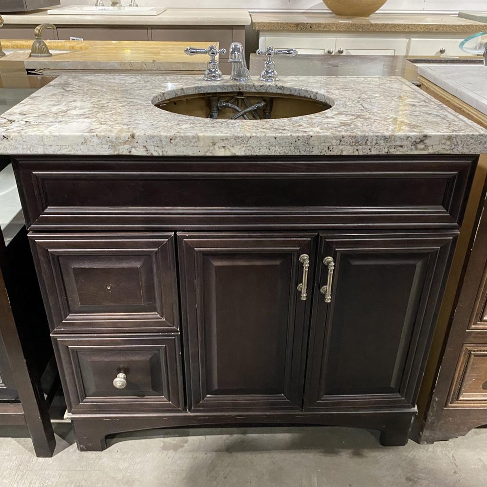 Mueble de baño oscuro con superficie de granito claro y grifería cromada