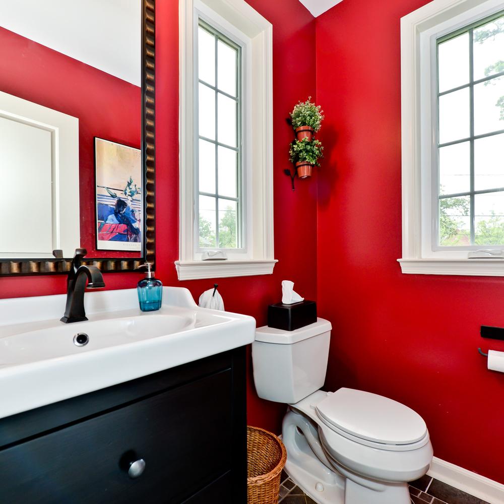 A cozy dark red bathroom with natural light and modern fixtures.