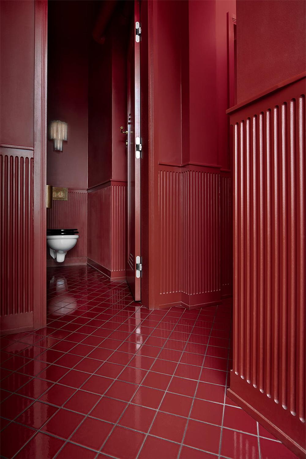 A bold and cohesive dark red bathroom with stylish paneling.