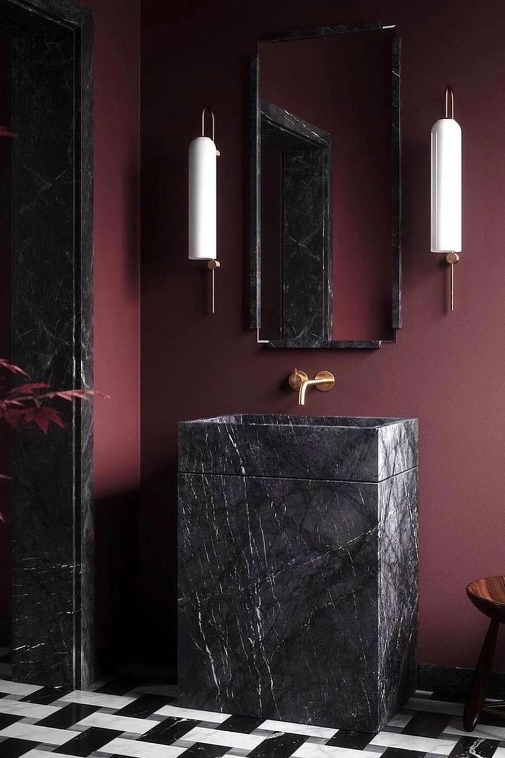 A lavish dark red bathroom with black marble accents.