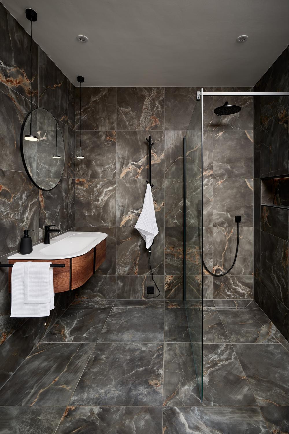 Baño sofisticado con azulejos oscuros y mármol