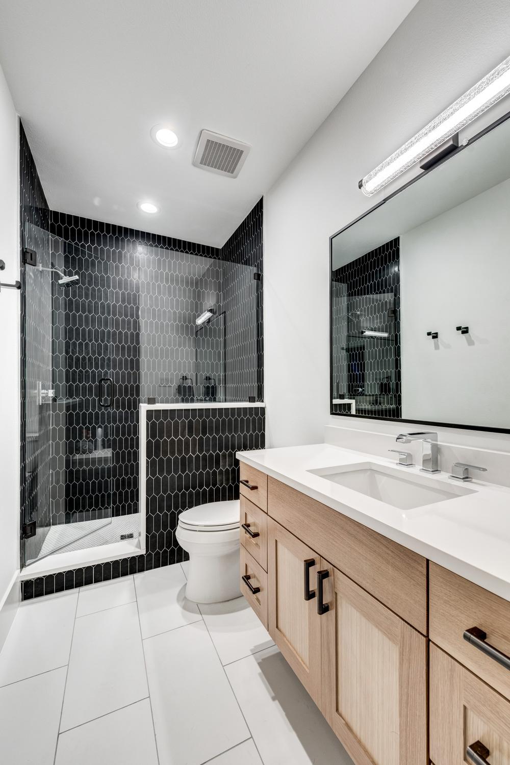 Baño luminoso y elegante con azulejos oscuros